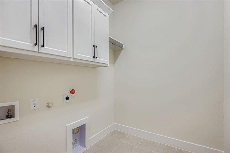 Laundry room featuring hookup for a gas dryer, light tile patterned floors, cabinet space, hookup for a washing machine, and hookup for an electric dryer Laundry room featuring hookup for a gas dryer, light tile patterned floors, cabinet space, hookup for a washing machine, and hookup for an electric dryer