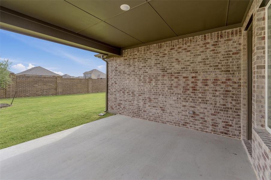 Covered concrete patio overlooking a manicured lawn