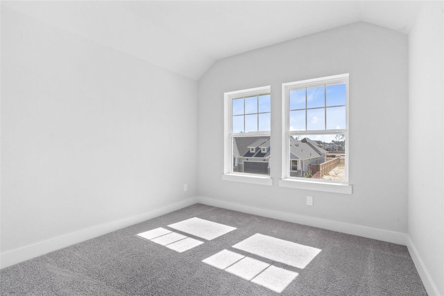 Step into this bright and airy room that balances unique design elements with everyday functionality, offering a tranquil space to unwind. The large windows illuminate the room's sloped ceiling and neutral tones, creating a cheerful and airy environment.