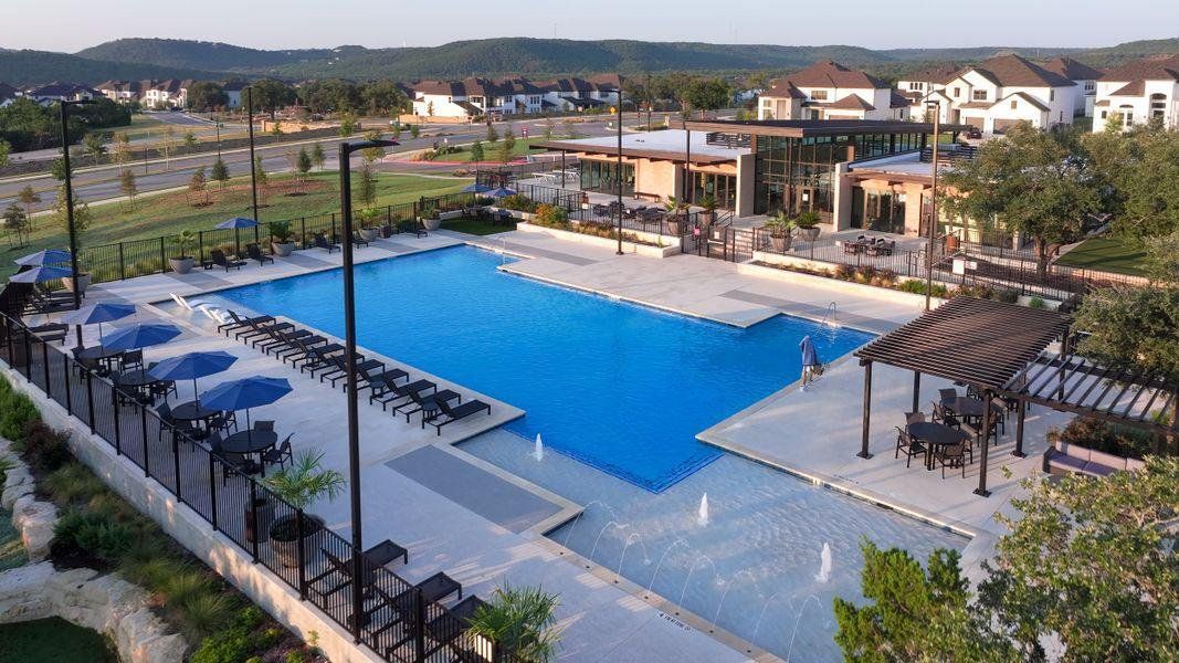 An aerial view showcases a resort-style swimming pool complex complete with fountains and shaded pergolas.