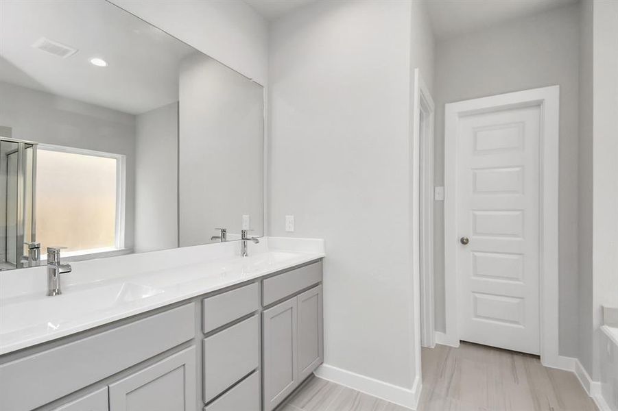 Enjoy a walk-in shower with tile surround, a separate garden tub with custom detailing, and an elegant vanity featuring light countertops, and modern hardware. Sample photo of completed home with similar floor plan. Actual colors and selections may vary.