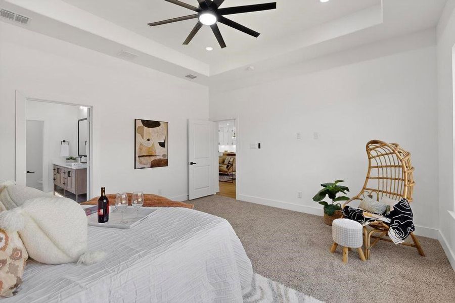 Bedroom featuring carpet floors, a raised ceiling, recessed lighting, a high ceiling, and connected bathroom