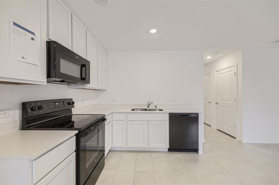 Kitchen featuring light countertops, white cabinets, black appliances, recessed lighting, and open floor plan