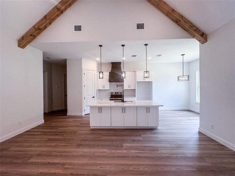 Kitchen featuring ventilation hood, beam ceiling, white cabinets, decorative backsplash, and light countertops Kitchen featuring ventilation hood, beam ceiling, white cabinets, decorative backsplash, and light countertops
