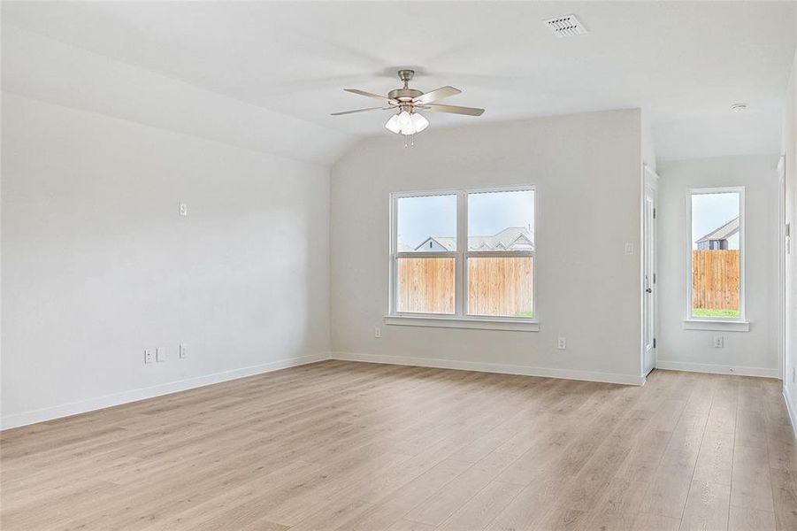 Empty room featuring light wood-type flooring, vaulted ceiling, and ceiling fan