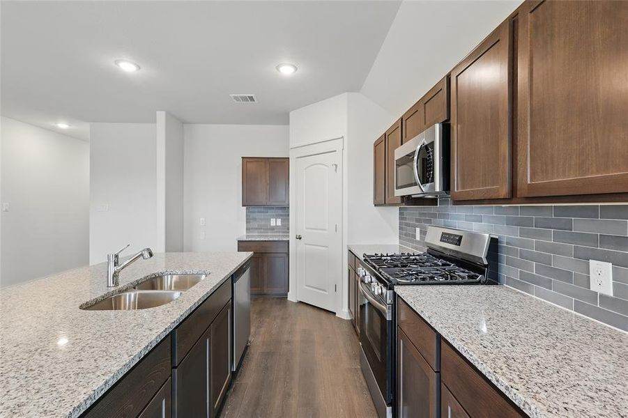 Kitchen featuring stainless steel appliances, dark wood-style flooring, backsplash, light stone counters, and recessed lighting Kitchen featuring stainless steel appliances, dark wood-style flooring, backsplash, light stone counters, and recessed lighting