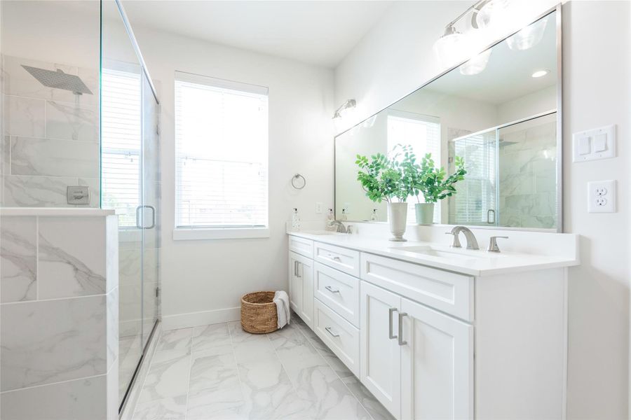 Double vanity with custom cabinetry, vanity lighting, and ample storage.