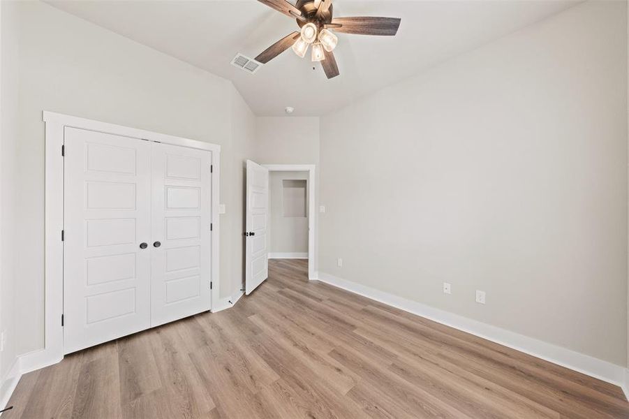 Unfurnished bedroom featuring light wood-style floors, a closet, ceiling fan, and lofted ceiling