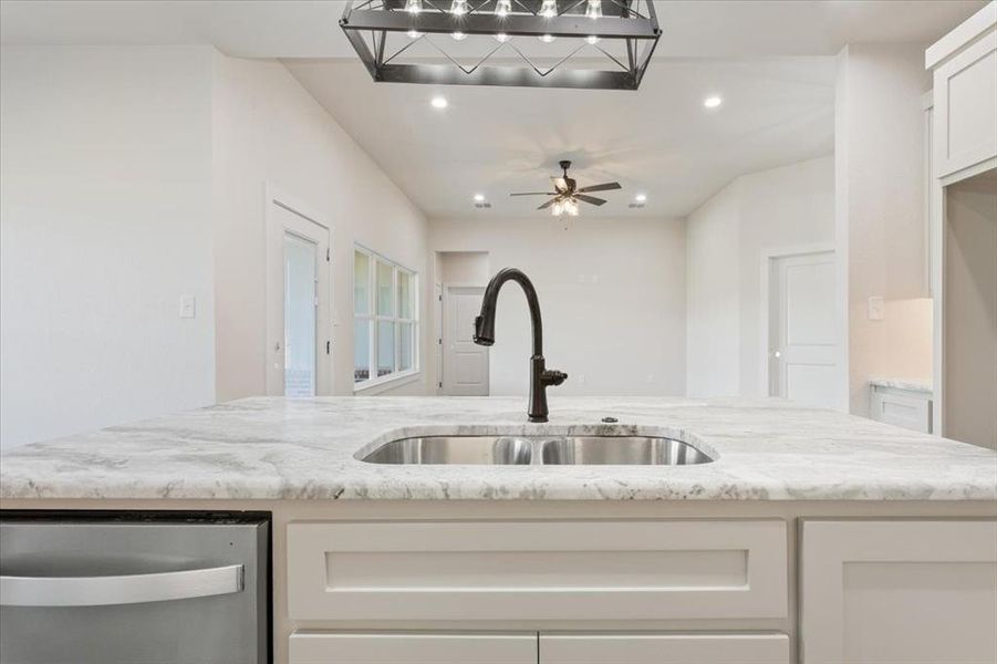 Kitchen with light stone counters, dishwasher, white cabinets, recessed lighting, and open floor plan