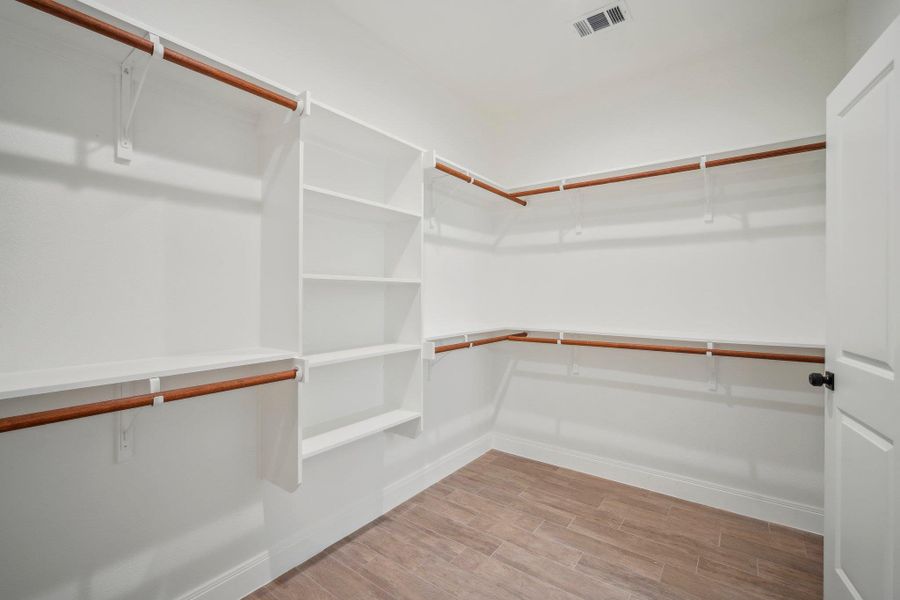 Spacious Primary closet featuring visible vents and wood finished floors