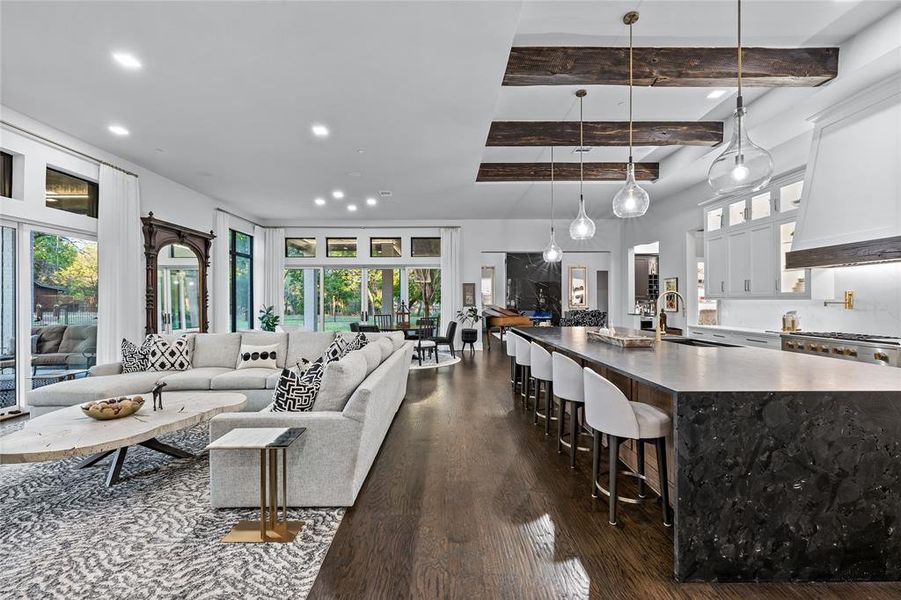 Living room with dark wood-type flooring, sink, beamed ceiling, and a healthy amount of sunlight