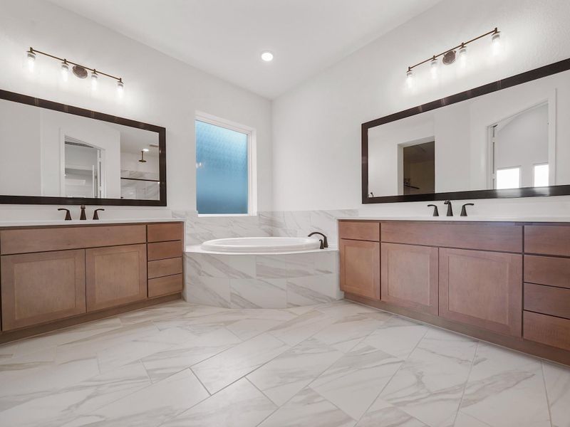 The spa-like ensuite bath features dual vanities, elegant quartz counters, and sleek fixtures, designed for both relaxation and everyday function.