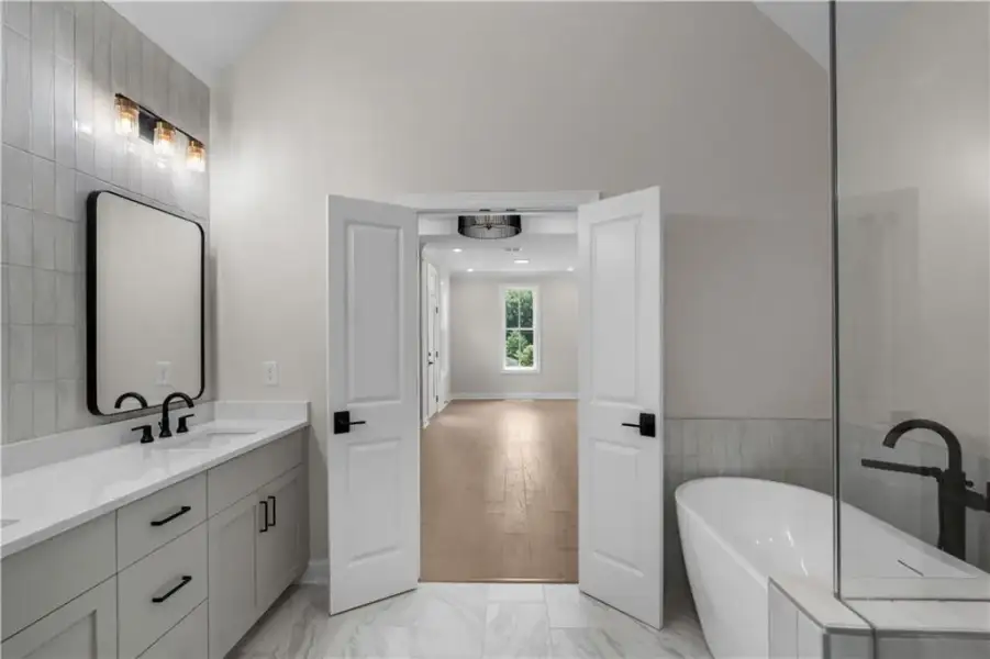 Dual vanity with quartz countertop, freestanding soaking tub, glass-enclosed shower, and tile flooring