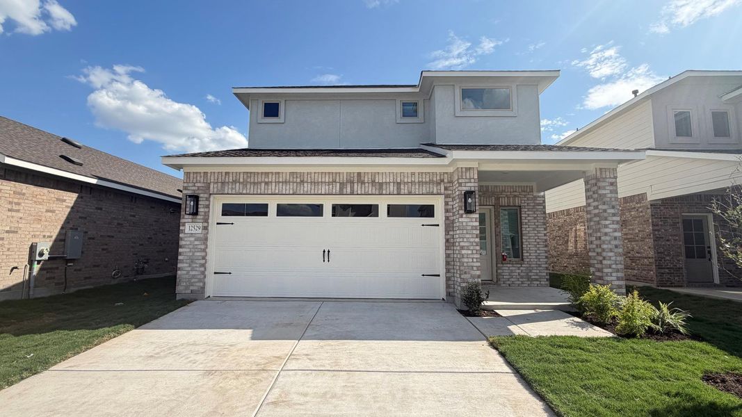 A modern two-story home with a brick and stucco facade, featuring an attached garage and a neatly manicured lawn. A modern two-story home with a brick and stucco facade, featuring an attached garage and a neatly manicured lawn.