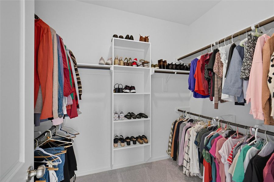 The second of TWO spacious walk-in closets featuring multiple hanging rods and shelving units, ideal for organizing clothing and shoes efficiently. The second of TWO spacious walk-in closets featuring multiple hanging rods and shelving units, ideal for organizing clothing and shoes efficiently.
