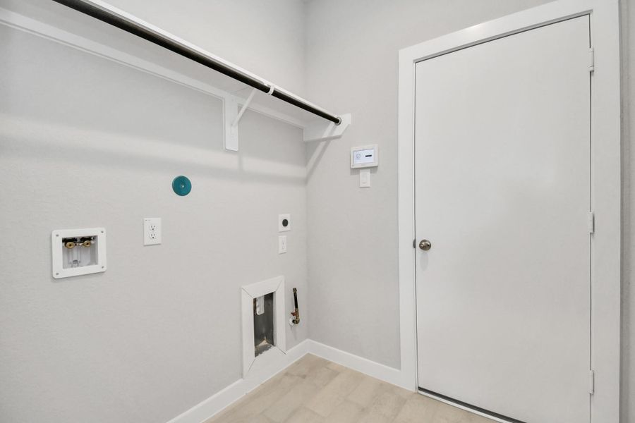 A spacious utility room with ample shelving for organization. It features connections for both gas and electric dryers, making it versatile and functional for all laundry needs. Sample photo of completed home with similar floor plan. Actual colors and selections may vary.