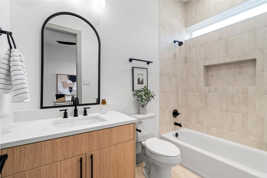 A beautifully appointed secondary bathroom with designer touches at every turn—featuring a floating wood vanity, quartz countertop, and a textured vertical tile surround with built-in niche. Matte black hardware and an arched mirror add a bold, modern edge to this serene and functional space. A beautifully appointed secondary bathroom with designer touches at every turn—featuring a floating wood vanity, quartz countertop, and a textured vertical tile surround with built-in niche. Matte black hardware and an arched mirror add a bold, modern edge to this serene and functional space.