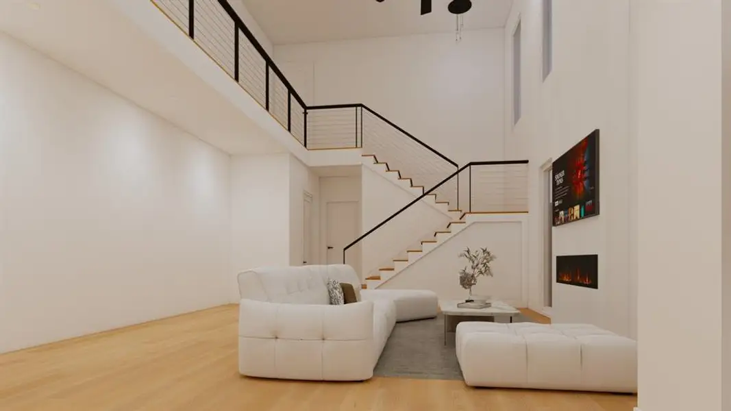 Living area featuring light wood-style flooring, a high ceiling, and a warm lit fireplace