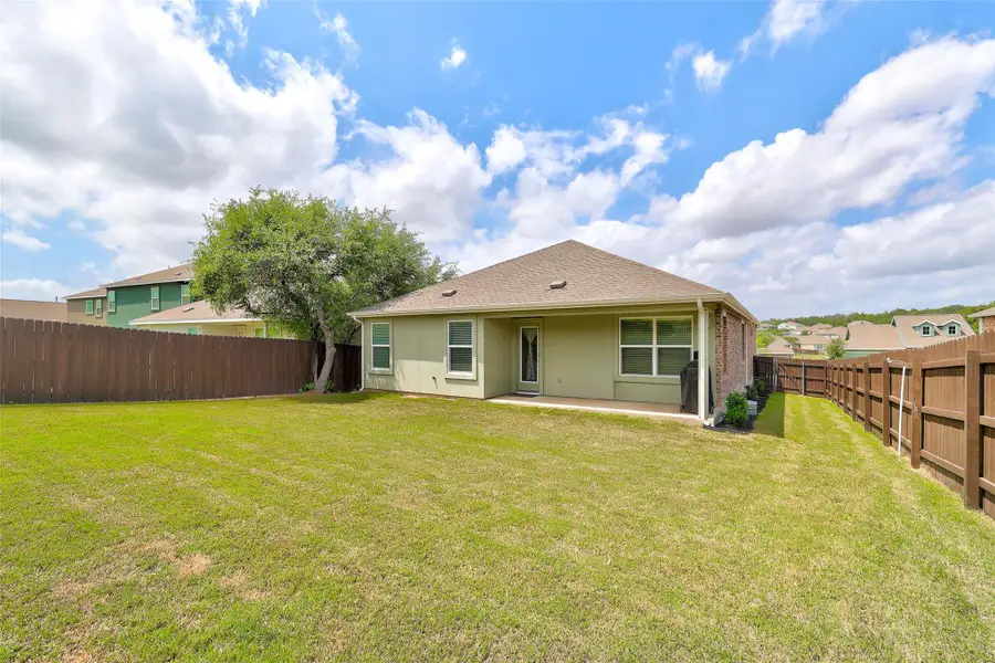 Spacious backyard featuring a manicured lawn, established tree, and a wood privacy fence