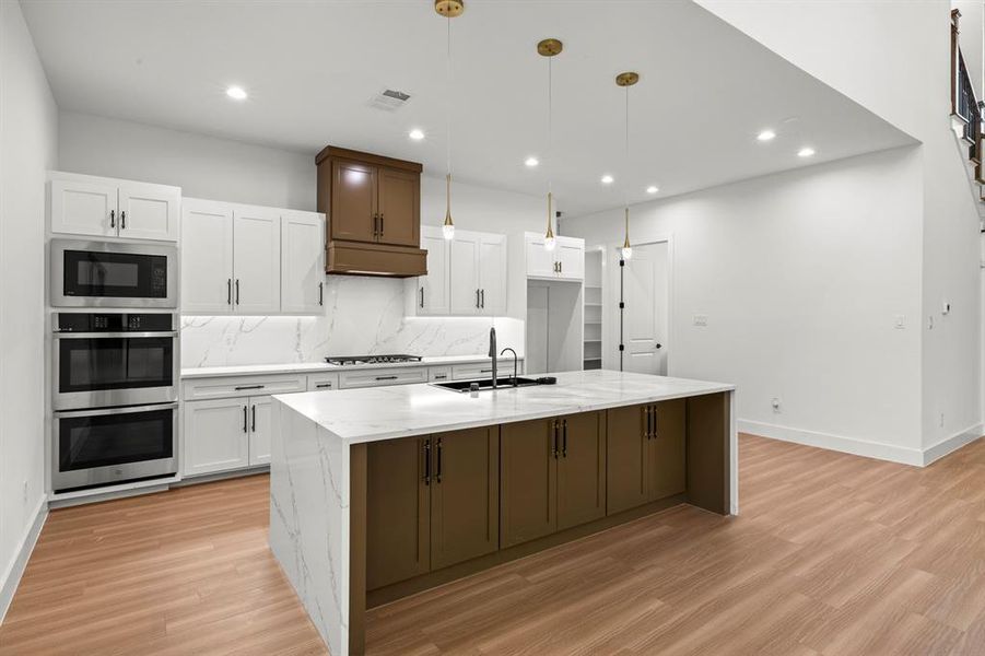 Waterfall quartz kitchen island and double ovens.