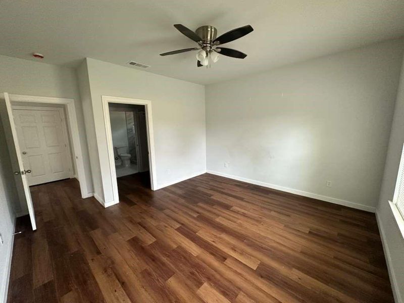 Unfurnished bedroom with dark wood finished floors, a ceiling fan, and ensuite bath