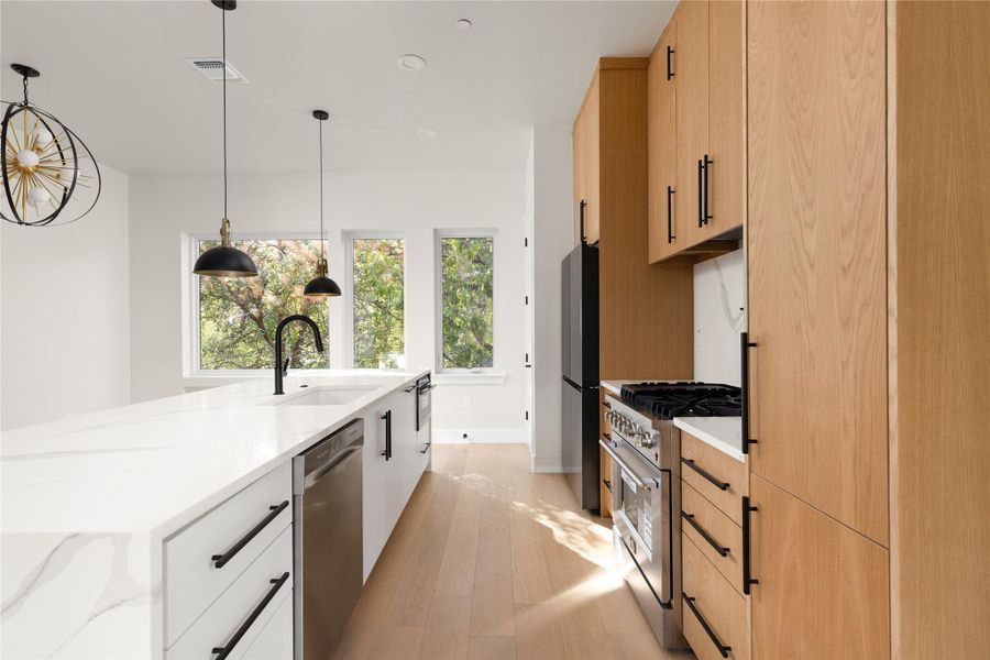 Warm wood cabinetry pairs with sleek stone countertops in this modern gourmet kitchen.