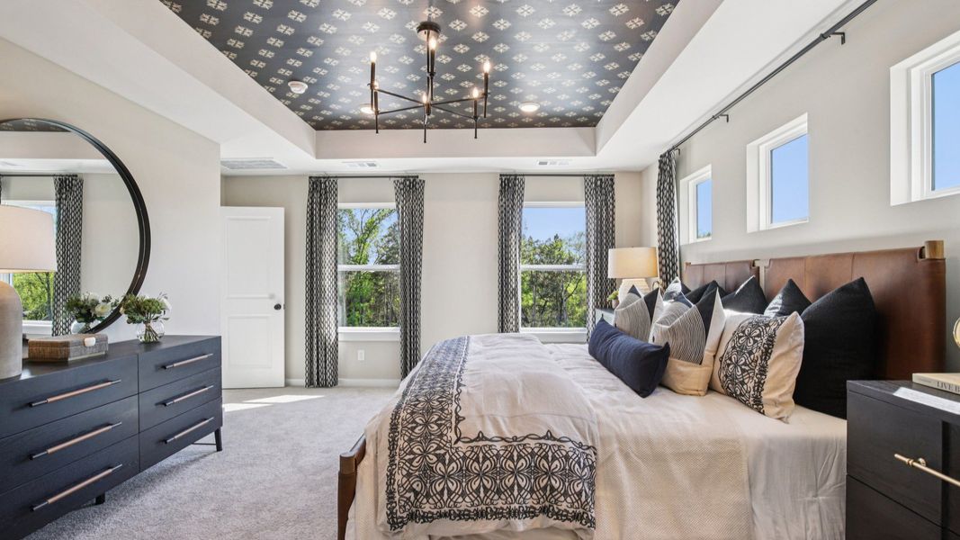 Large Primary bedroom with accent tray ceiling and multiple windows for natural light