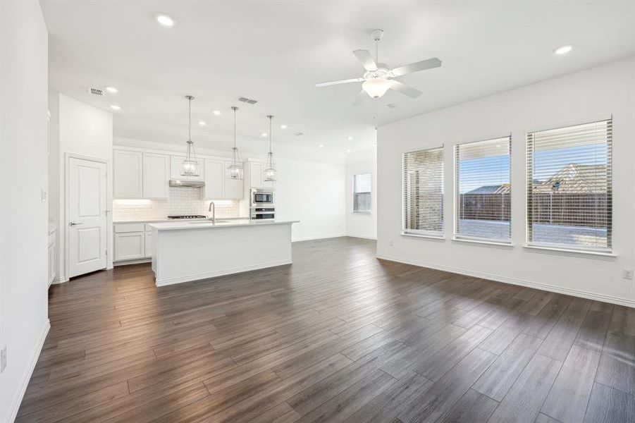 Unfurnished living room featuring dark wood-type flooring, ceiling fan, and sink