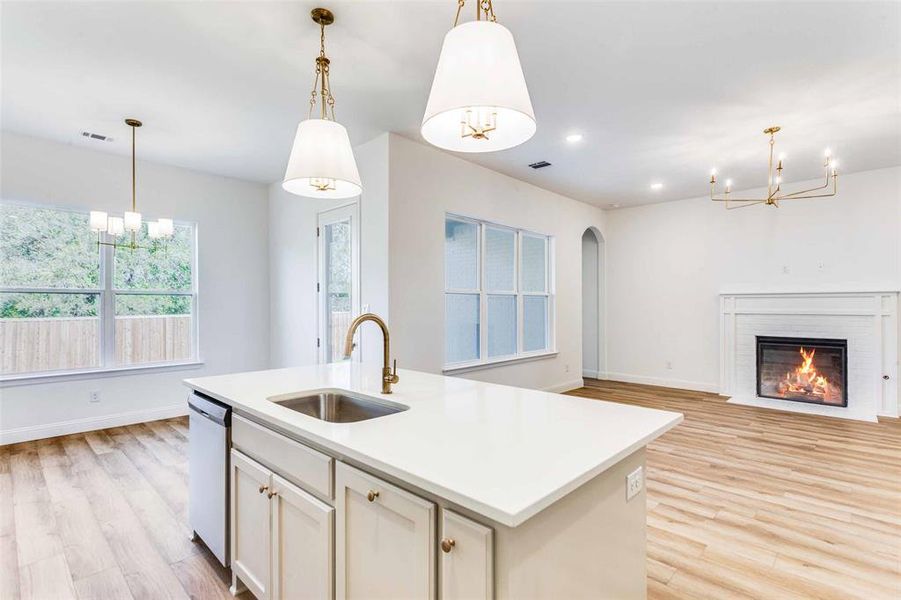 Kitchen featuring a center island with sink, sink, hanging light fixtures, light hardwood / wood-style flooring, and stainless steel dishwasher