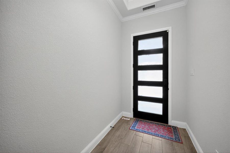 Entryway featuring light wood-type flooring and crown molding
