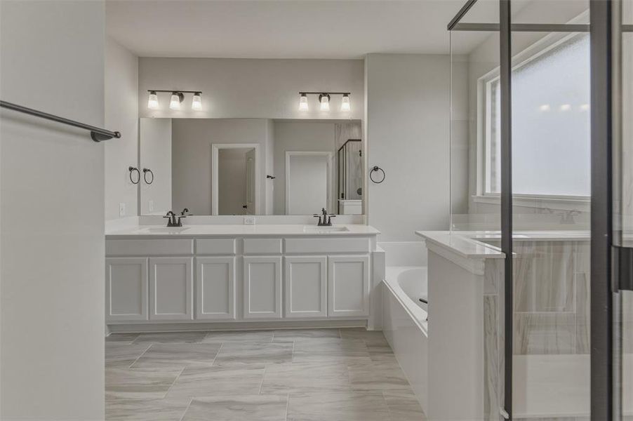 Bathroom with a dual vanity featuring white shaker-style cabinetry, a light-toned countertop, and dual rectangular sinks with dark bronze fixtures Bathroom with a dual vanity featuring white shaker-style cabinetry, a light-toned countertop, and dual rectangular sinks with dark bronze fixtures