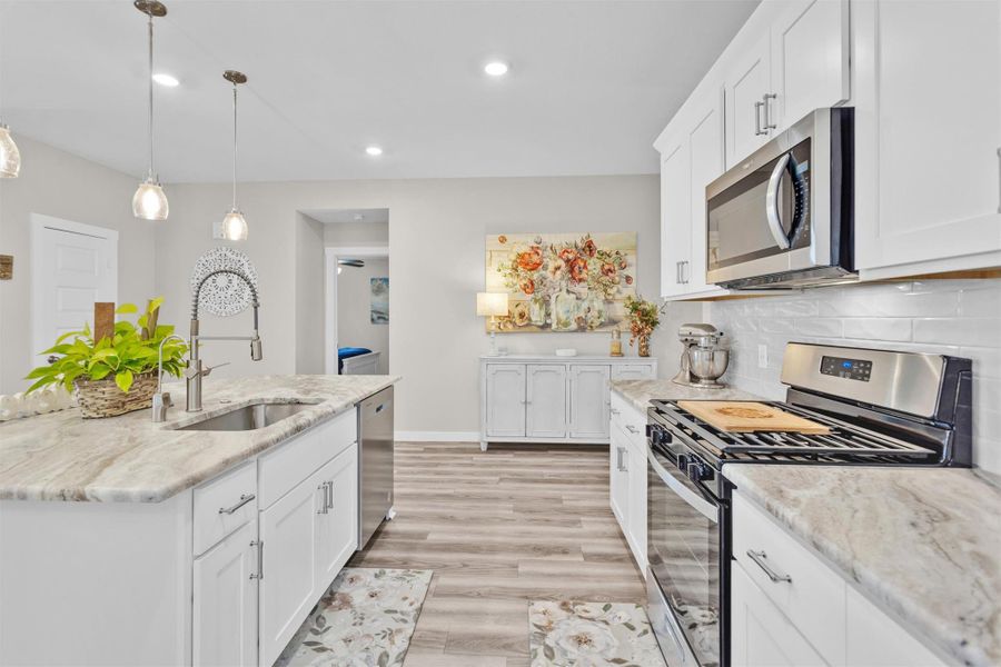 Another view of this incredible kitchen. Stainless Steel appliances, sleek subway tile, and leathered granite counters create a warm and inviting kitchen.