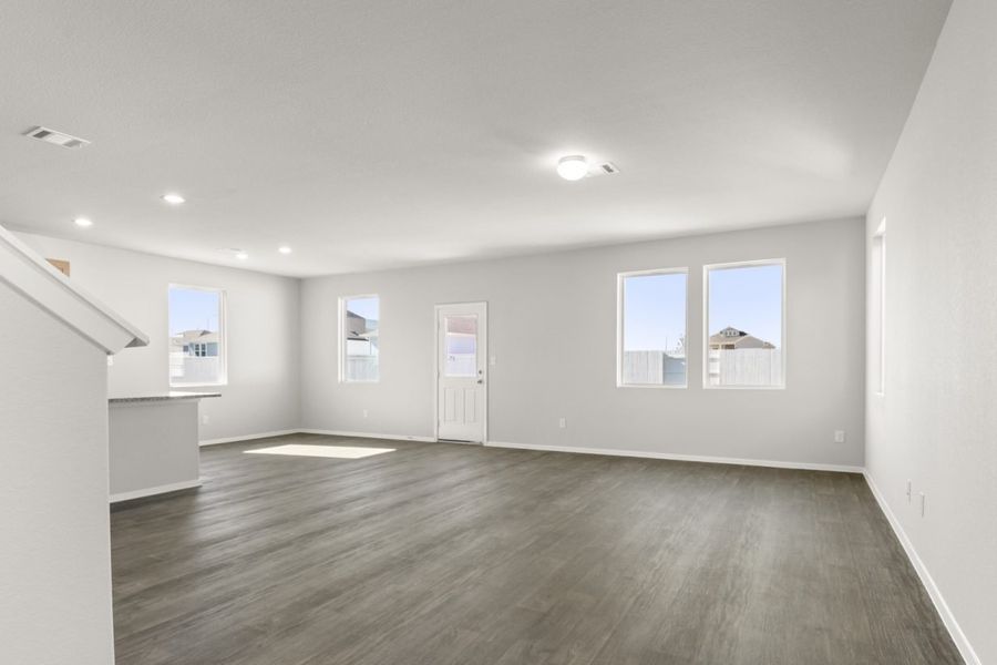 Image of a living room with brown vinyl flooring, light grey walls, and four large windows