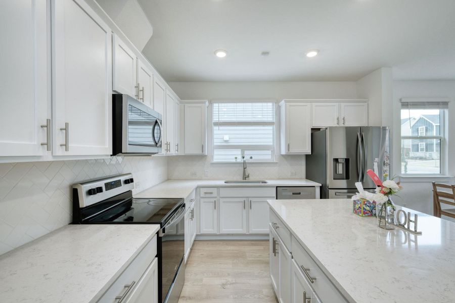 Kitchen featuring white cabinets, plenty of natural light, stainless steel appliances, and a sink