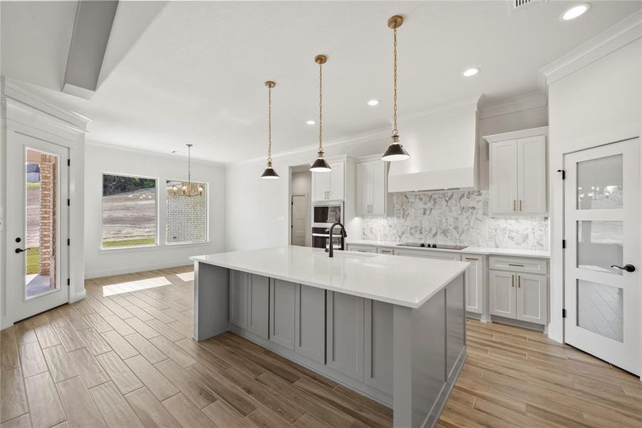 Kitchen with backsplash, white cabinetry, decorative light fixtures, gray cabinets, and crown molding
