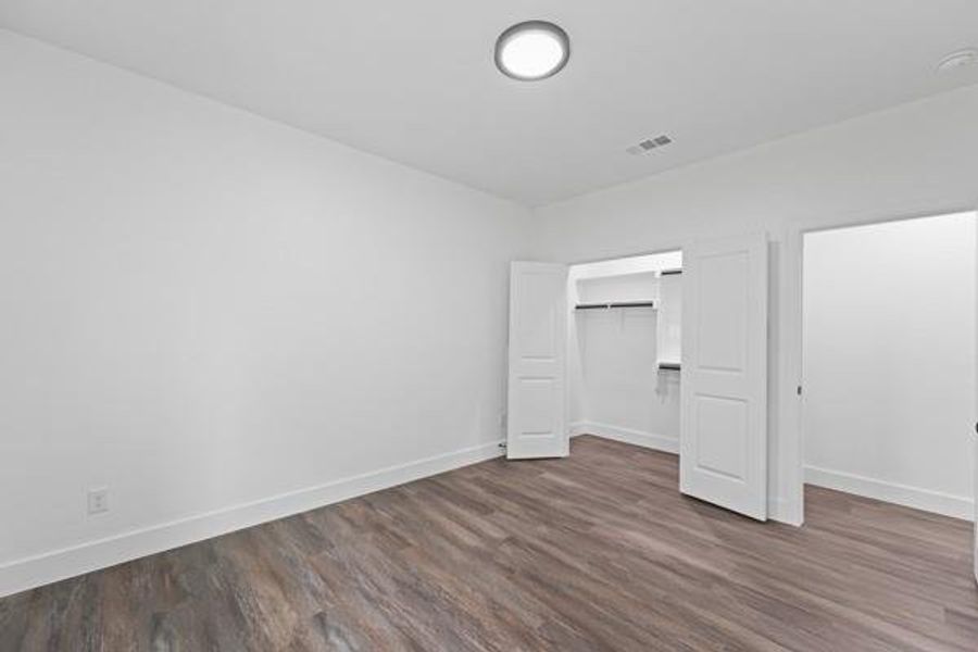 Room featuring wood-finish flooring, white baseboards, a single window, and a flush-mount ceiling light Room featuring wood-finish flooring, white baseboards, a single window, and a flush-mount ceiling light