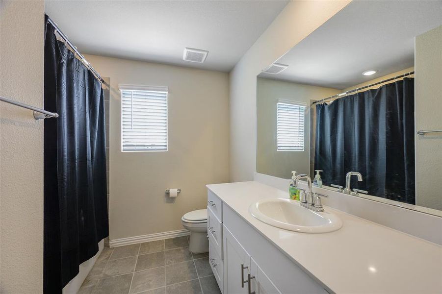 Bathroom featuring a white vanity with an undermount sink, a large mirror, and tile flooring Bathroom featuring a white vanity with an undermount sink, a large mirror, and tile flooring