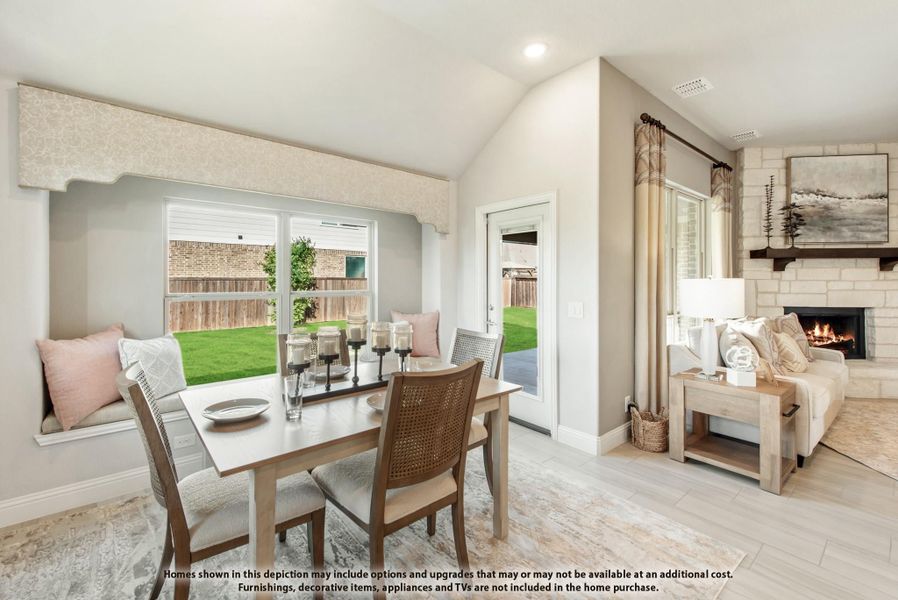 Dining area with built-in bench seating and large window, open to living room with stone fireplace and vaulted ceiling