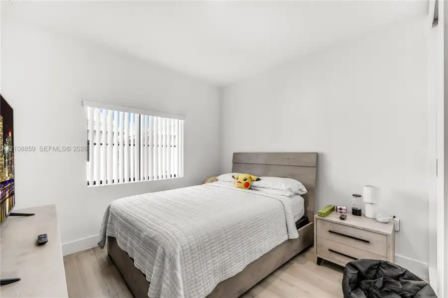 Neutral-toned walls, wood-finish flooring, and white vertical window blinds