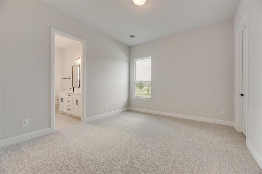 Unfurnished bedroom featuring light carpet and connected bathroom