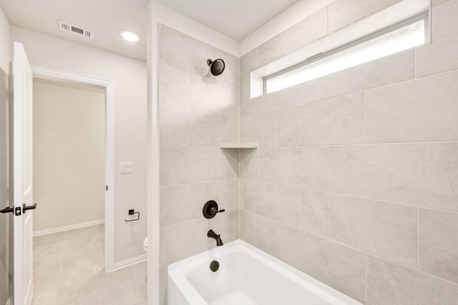 Bathtub and shower combo with large gray tile surround, dark bronze fixtures, and a small window above Bathtub and shower combo with large gray tile surround, dark bronze fixtures, and a small window above