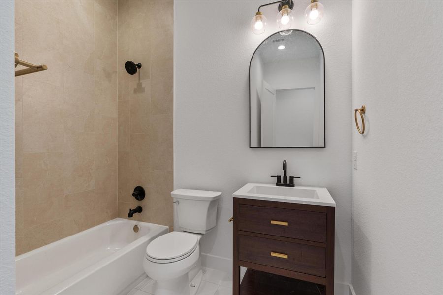 A well-appointed bathroom features a dark wood vanity, modern fixtures, and a tiled shower-over-tub combination.