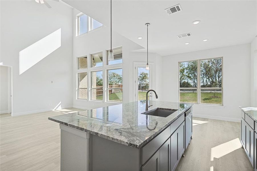 Kitchen featuring a wealth of natural light, sink, a kitchen island with sink, and hanging light fixtures