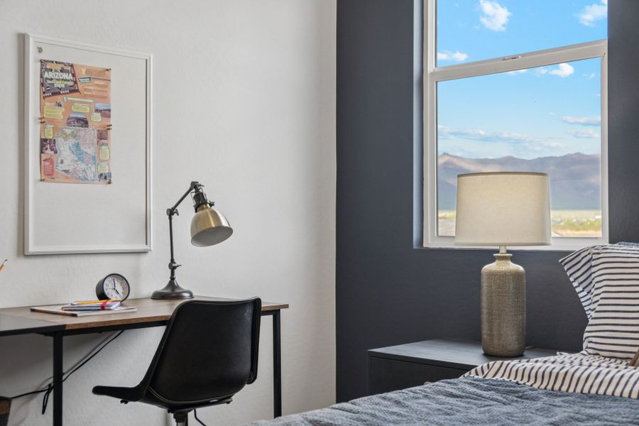 A bedroom with a desk and a lamp.