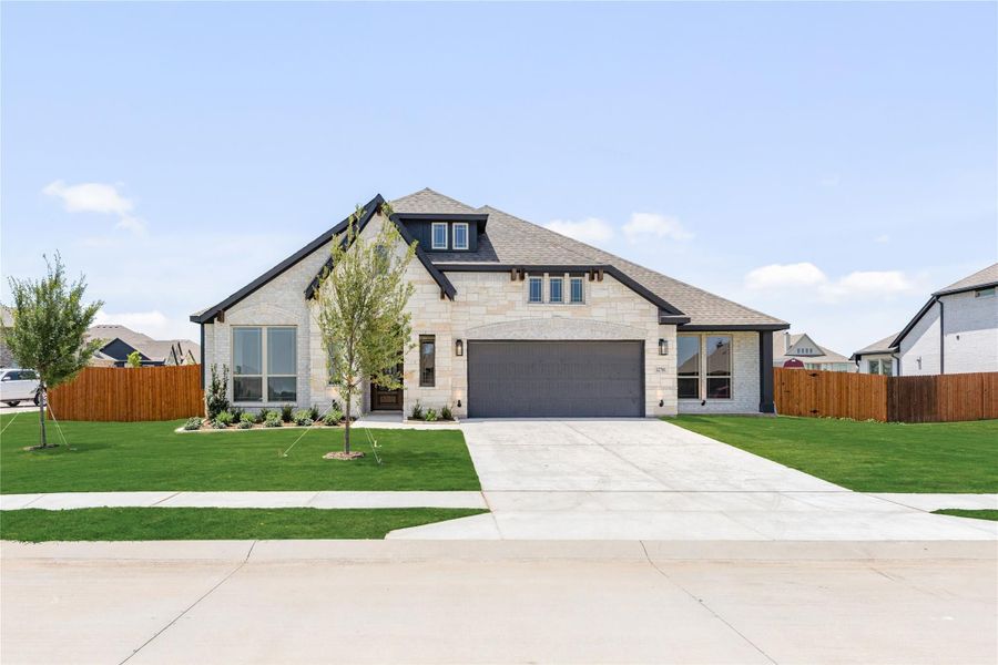 Single-story home with light stone exterior, two-car garage, and green front lawn