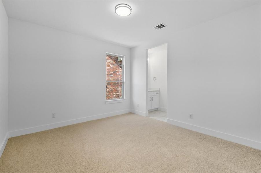 Unfurnished bedroom with light colored carpet and ensuite bathroom
