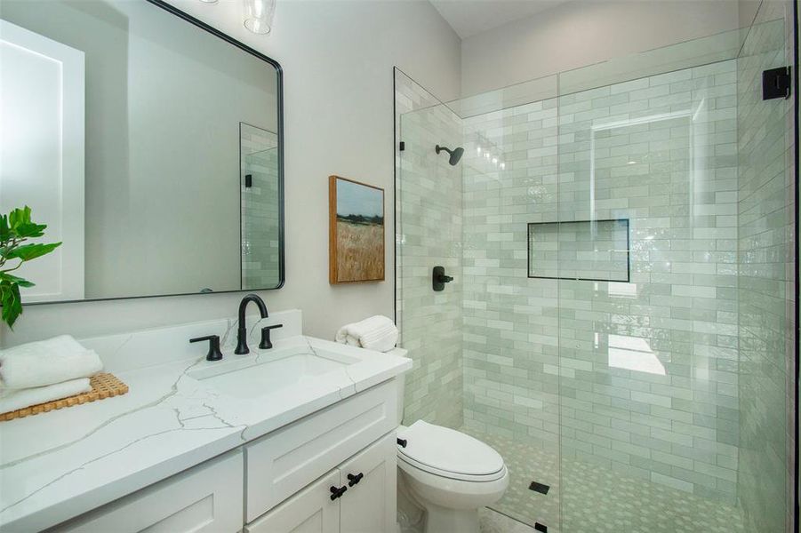 Bathroom featuring vanity, toilet, and a shower with door