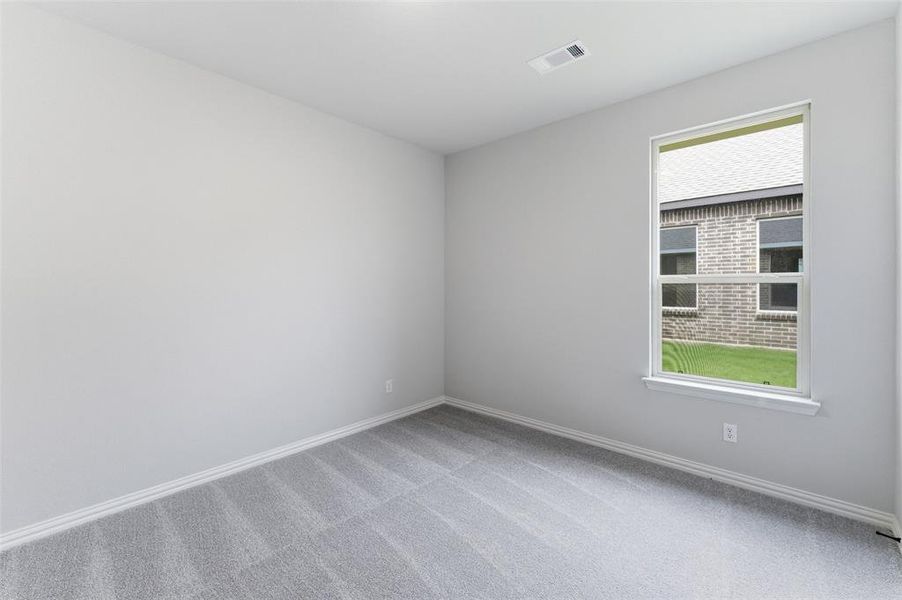 Bright interior room featuring a single window, light gray carpeting, and neutral wall paint