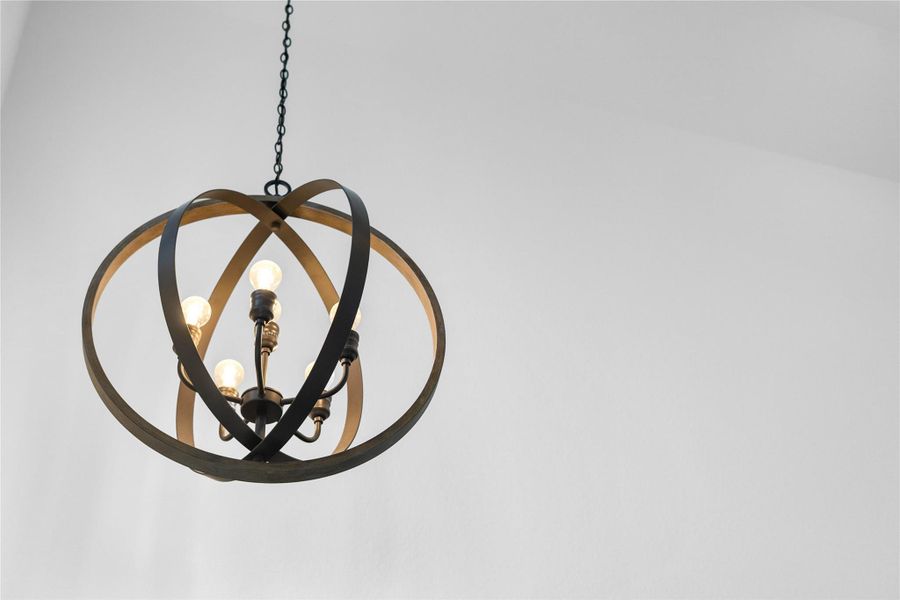 A striking, large-scale orb-style chandelier, which serves as a focal point in the room. This contemporary fixture features an open, spherical frame constructed from metal with a rich oil-rubbed bronze finish, providing a modern yet rustic aesthetic.