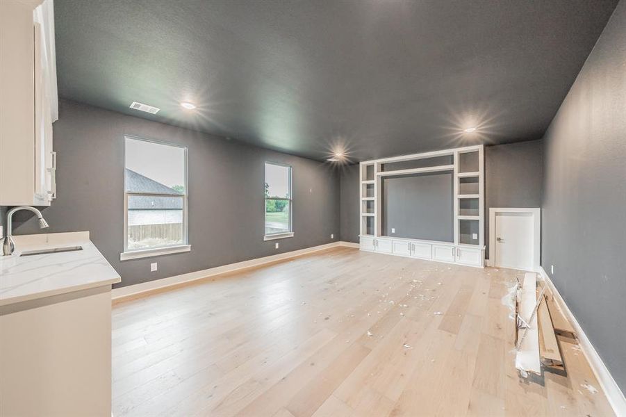 Unfurnished living room featuring light wood-type flooring and built in features